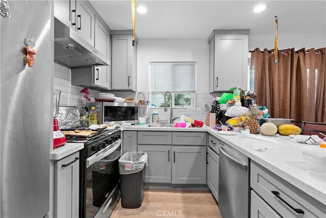 kitchen featuring sink, light stone counters, gray cabinetry, and appliances with stainless steel finishes