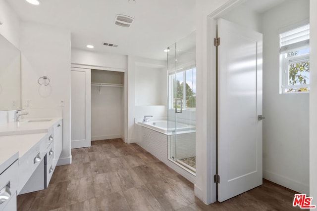 bathroom featuring hardwood / wood-style flooring, vanity, and independent shower and bath