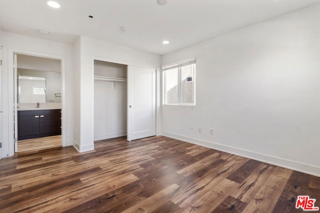 unfurnished bedroom featuring dark hardwood / wood-style floors, sink, ensuite bath, and a closet