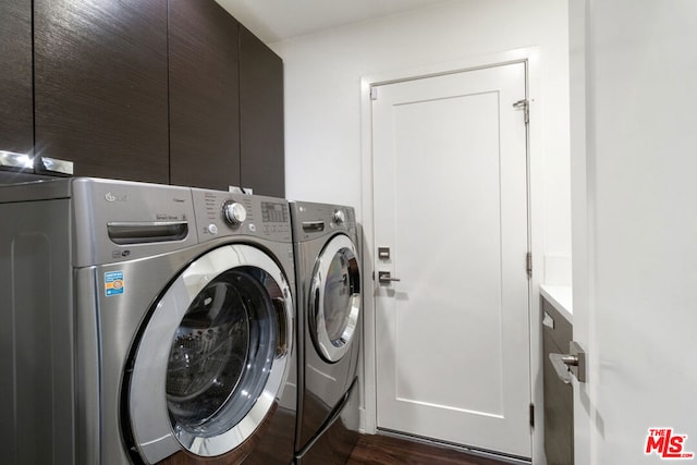 clothes washing area featuring dark wood-type flooring, washing machine and dryer, and cabinets