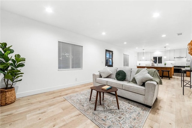 living room with visible vents, recessed lighting, baseboards, and light wood finished floors