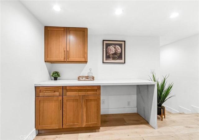 interior space featuring light wood finished floors, brown cabinets, recessed lighting, and light countertops