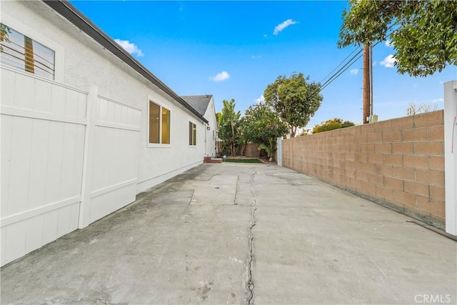 exterior space with stucco siding, a patio, and a fenced backyard