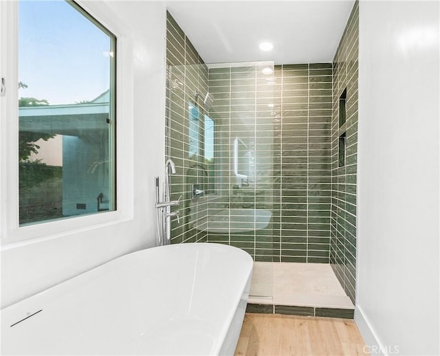 bathroom featuring a freestanding tub, wood finished floors, and a tile shower