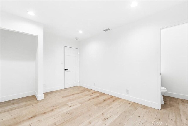 empty room featuring visible vents, recessed lighting, baseboards, and wood-type flooring