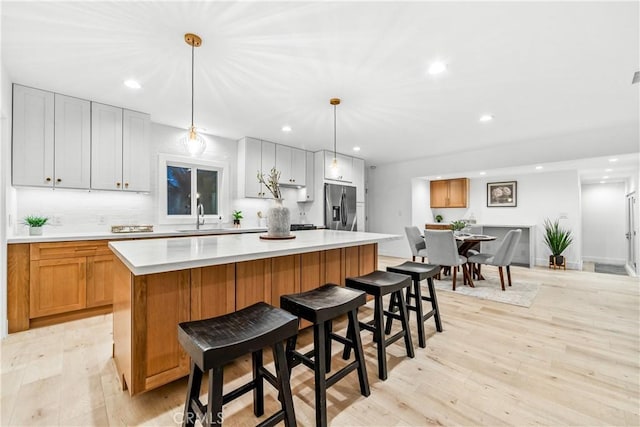 kitchen featuring white cabinetry, hanging light fixtures, a center island, stainless steel refrigerator with ice dispenser, and light hardwood / wood-style floors