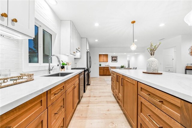 kitchen featuring light hardwood / wood-style floors, sink, hanging light fixtures, and white cabinets