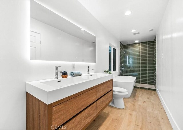 full bathroom featuring vanity, hardwood / wood-style flooring, plus walk in shower, and toilet