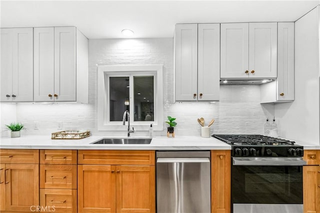 kitchen featuring backsplash, under cabinet range hood, light countertops, stainless steel appliances, and a sink