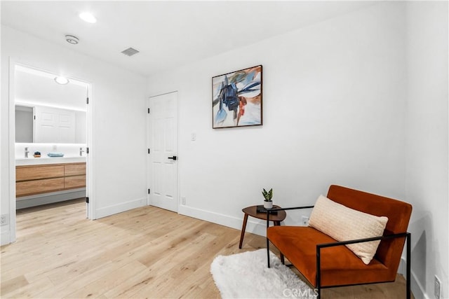 sitting room with visible vents, baseboards, and light wood-style flooring