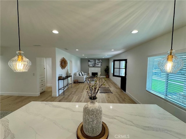 interior space featuring pendant lighting, lofted ceiling, light stone countertops, and light hardwood / wood-style flooring