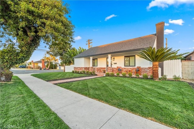 ranch-style house with a front lawn, stucco siding, brick siding, and a chimney