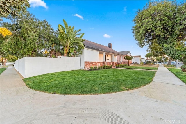 view of side of home featuring brick siding, a lawn, and fence