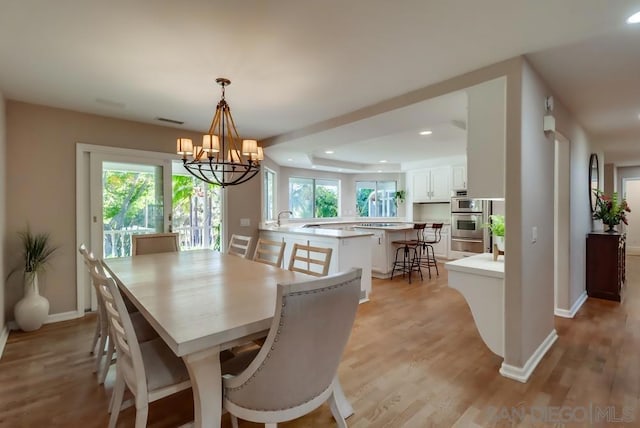 dining room featuring sink, light hardwood / wood-style flooring, and an inviting chandelier