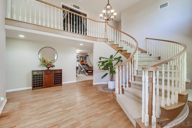 entrance foyer with hardwood / wood-style flooring, a notable chandelier, and a towering ceiling