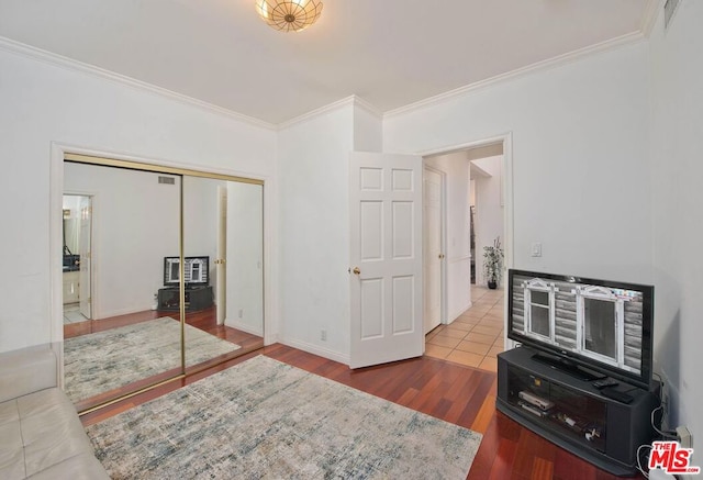 bedroom with wood-type flooring, a closet, and ornamental molding