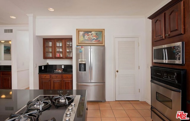 kitchen featuring ornamental molding, light tile patterned flooring, and appliances with stainless steel finishes