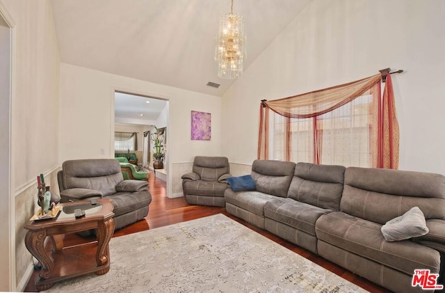 living room featuring hardwood / wood-style floors, vaulted ceiling, and a notable chandelier