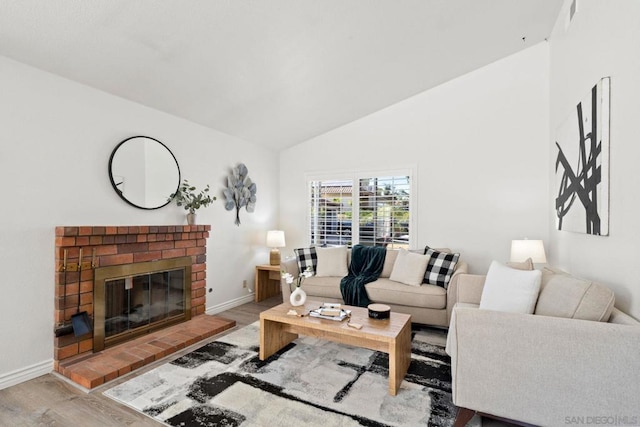 living room with light wood-type flooring, a brick fireplace, and lofted ceiling