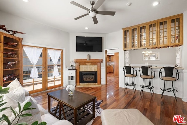 living room with a tiled fireplace, dark hardwood / wood-style floors, and ceiling fan