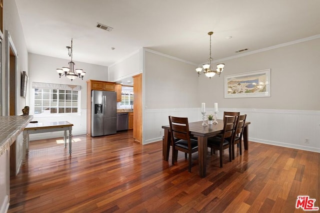 dining area featuring dark hardwood / wood-style flooring, crown molding, and an inviting chandelier