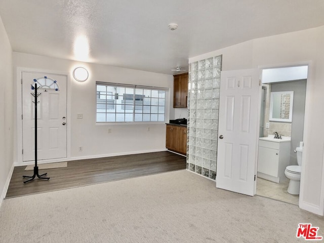 unfurnished living room featuring sink and carpet