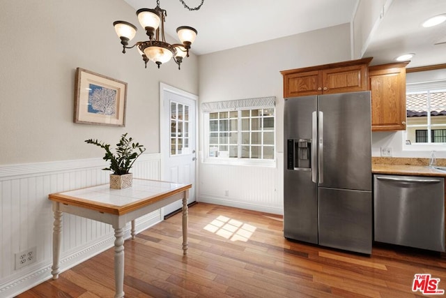 kitchen with an inviting chandelier, stainless steel appliances, and wood-type flooring