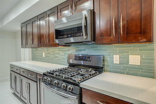 kitchen featuring light tile patterned flooring, light stone counters, decorative backsplash, and appliances with stainless steel finishes