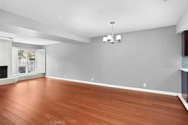 unfurnished living room featuring hardwood / wood-style floors, a chandelier, and a large fireplace