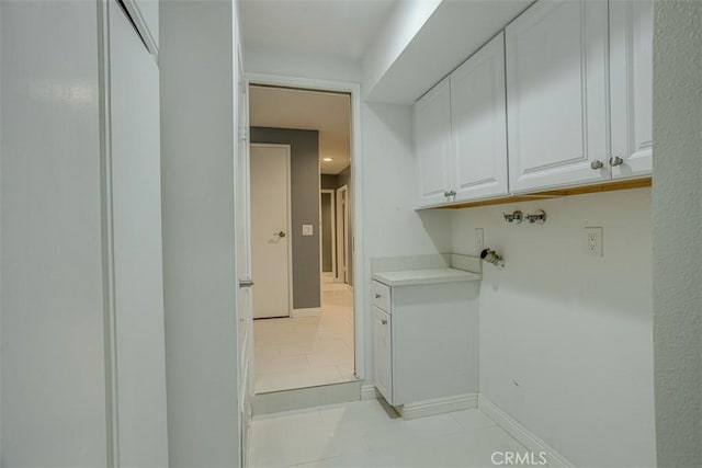 laundry area featuring light tile patterned floors and cabinets