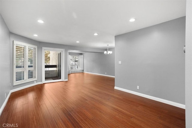 unfurnished living room with a notable chandelier and wood-type flooring