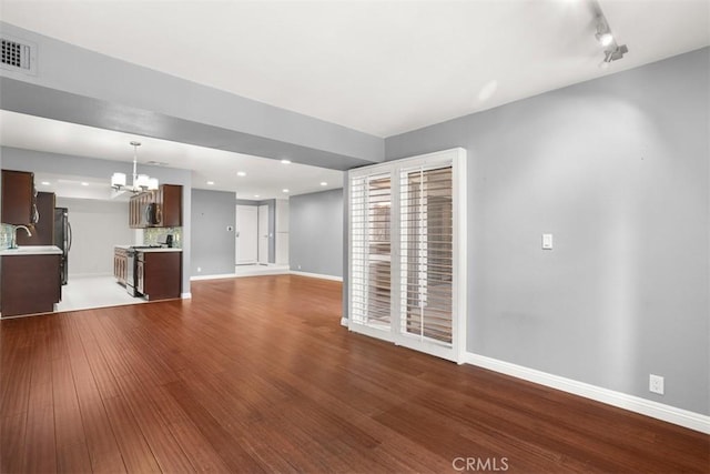 unfurnished living room with hardwood / wood-style flooring and a notable chandelier