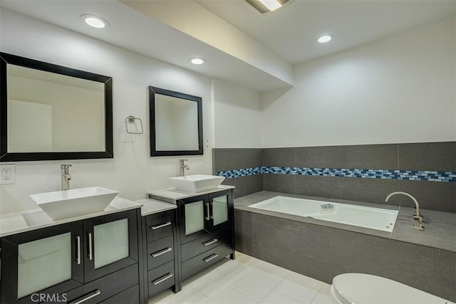 bathroom with vanity, toilet, tile patterned floors, and a relaxing tiled tub