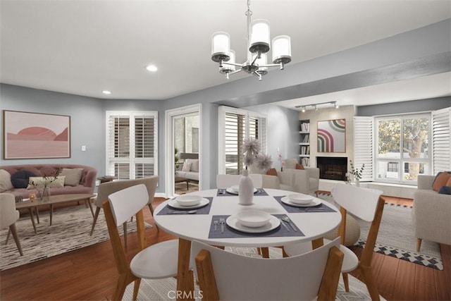 dining space with hardwood / wood-style floors, an inviting chandelier, and a large fireplace