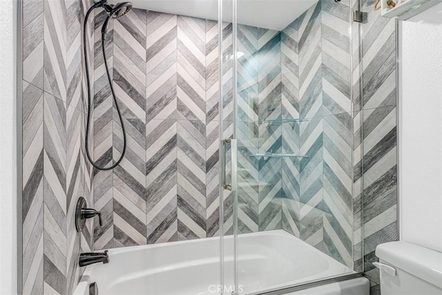 bathroom featuring toilet and combined bath / shower with glass door