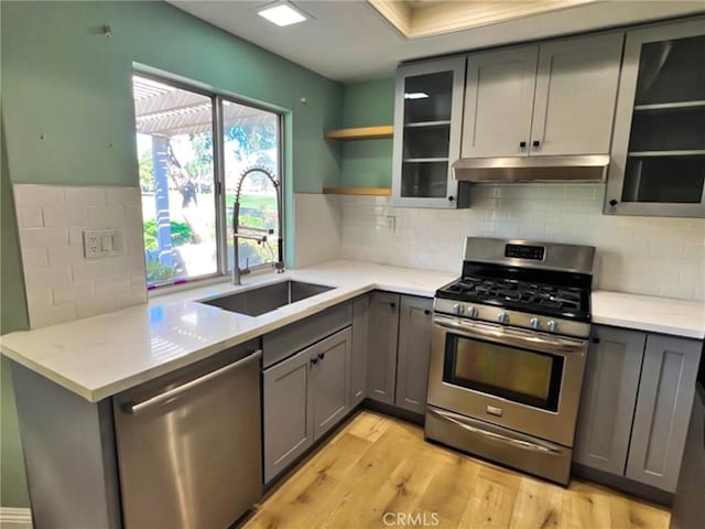 kitchen featuring light stone counters, stainless steel appliances, gray cabinets, and sink