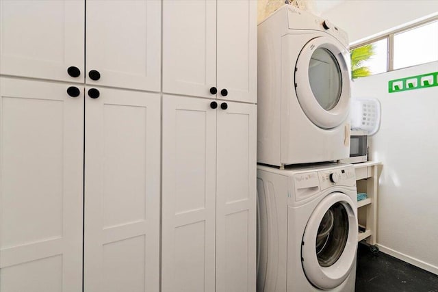 clothes washing area featuring stacked washer / dryer and cabinets