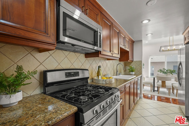 kitchen featuring stainless steel appliances, dark stone countertops, decorative backsplash, sink, and light tile patterned flooring