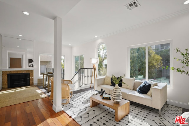 living room with light hardwood / wood-style floors, plenty of natural light, crown molding, and a tiled fireplace