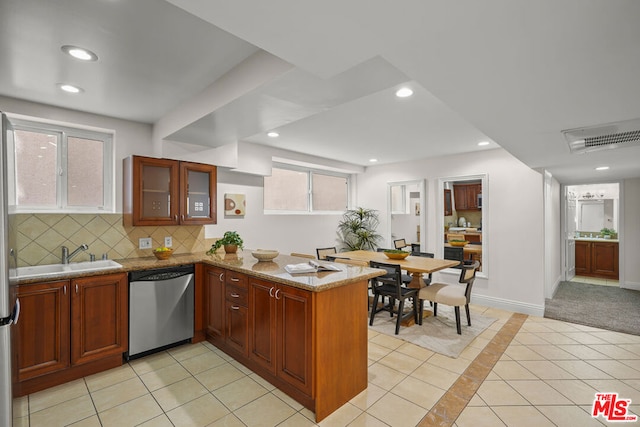 kitchen with dishwasher, sink, kitchen peninsula, light stone counters, and light tile patterned floors