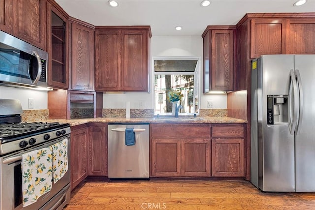 kitchen featuring light stone countertops, sink, light hardwood / wood-style flooring, and stainless steel appliances