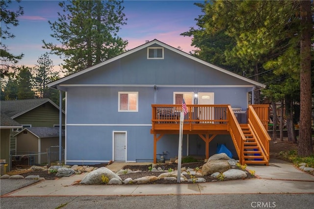 back house at dusk featuring a wooden deck