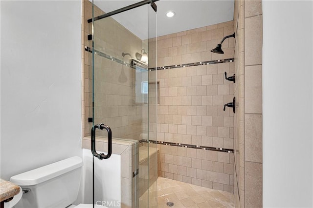 bathroom with a shower with shower door and toilet