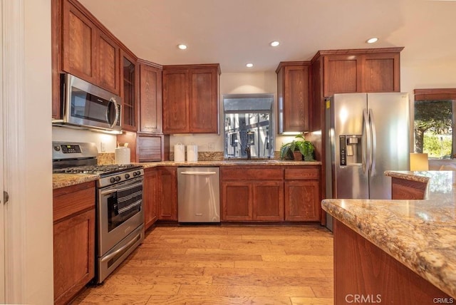 kitchen featuring sink, light hardwood / wood-style flooring, light stone countertops, and stainless steel appliances