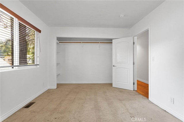 unfurnished bedroom featuring light colored carpet and a closet