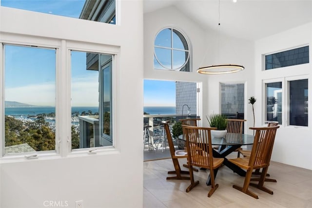 dining space featuring a high ceiling, a wealth of natural light, and a water view