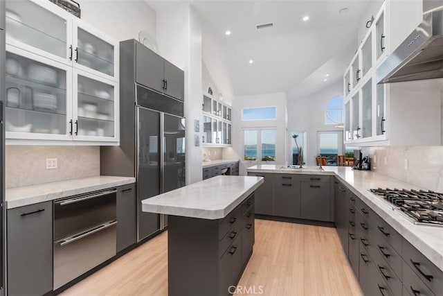 kitchen featuring wall chimney range hood, a center island, built in refrigerator, and decorative backsplash