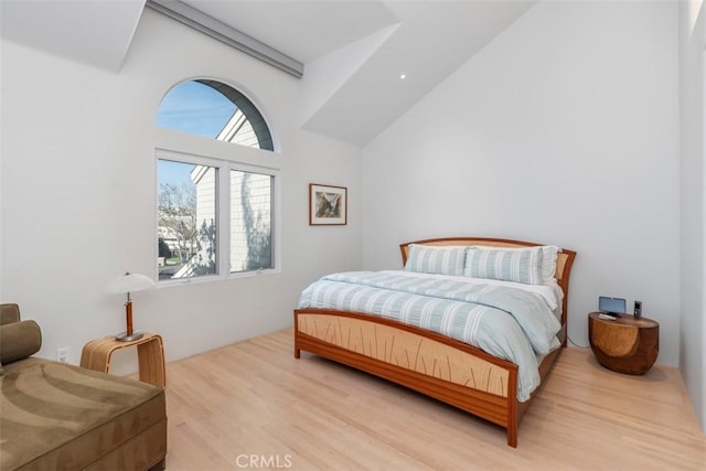 bedroom with light hardwood / wood-style flooring and a towering ceiling