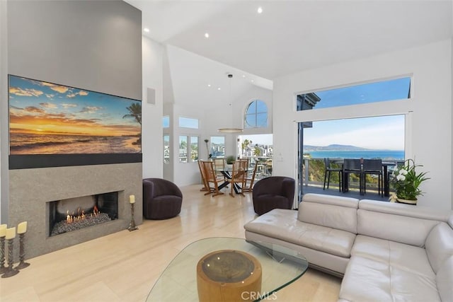 living room with hardwood / wood-style flooring, a water view, and a high ceiling