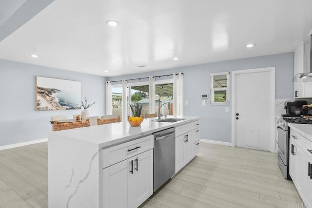 kitchen featuring sink, white cabinetry, a center island with sink, light hardwood / wood-style flooring, and appliances with stainless steel finishes